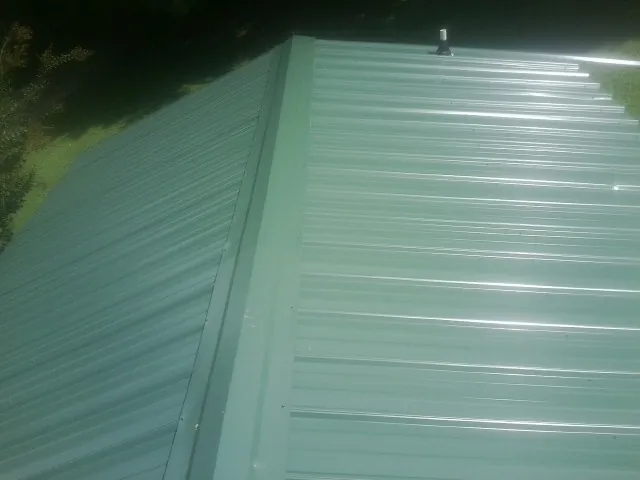 New green metal panels meeting at the ridge of a roof — Flat Roof Repair work by our crew in Stoddard