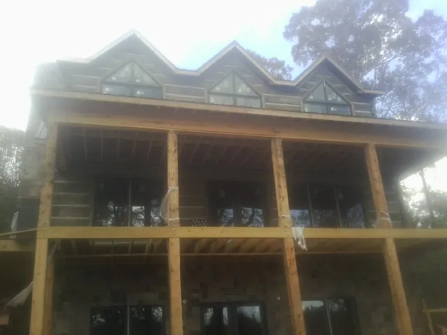 Dormers and porch framing on a large log home under construction — Roof Coating work by our crew in Stoddard