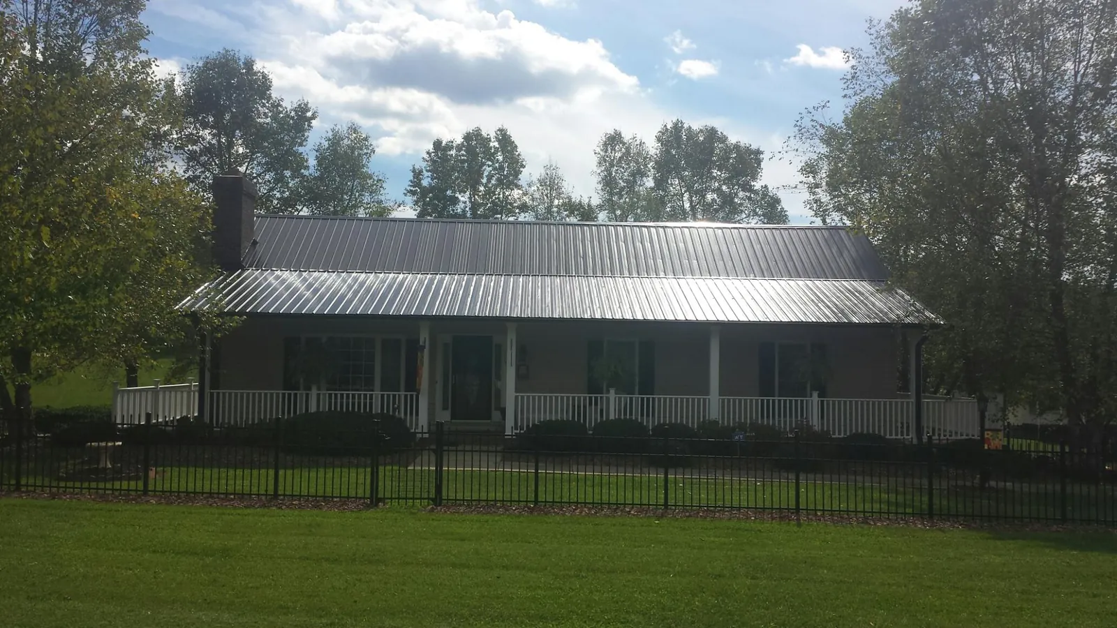 Gray metal roof on a brick ranch with a full width front porch — Gutter Guard Installation work by our crew in Stoddard