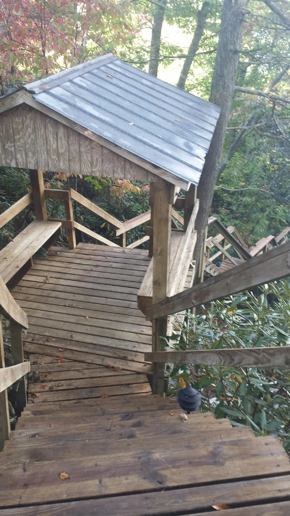 Metal roofed shelter over wooden steps on a wooded walkway — Skylight Repair & Installation work by our crew in Stoddard