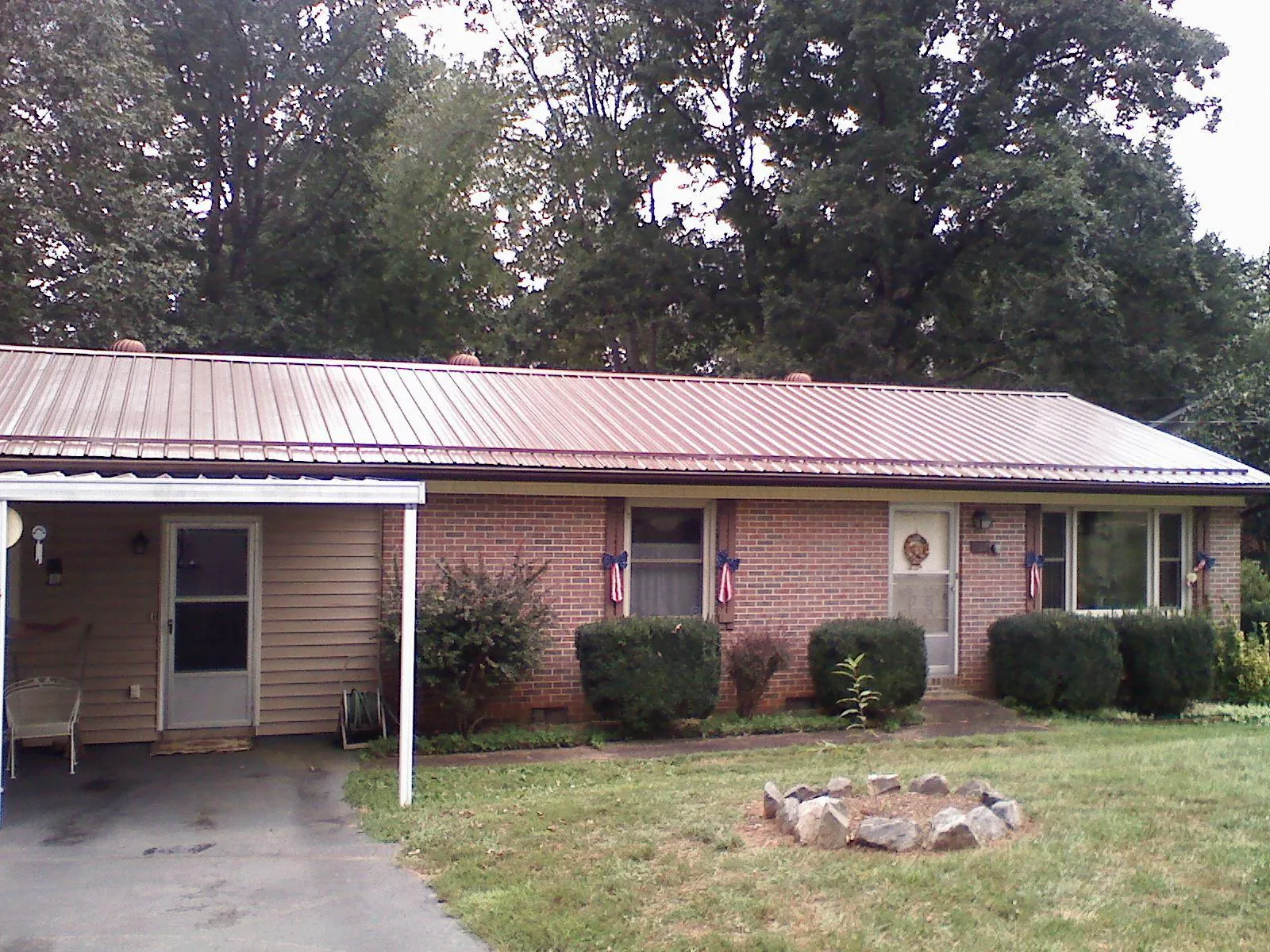 Bronze metal roof and carport on a brick ranch home — Roof Repair work by our crew in Stoddard
